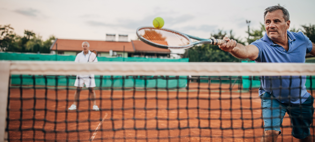 Two elderly men playing tennis.